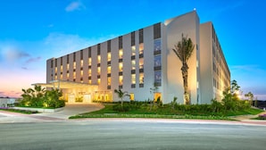 A modern hotel with a large entrance, multiple floors, and a well-lit facade. - City Express Plus by Marriott Cancún Aeropuerto Riviera (Cancun)