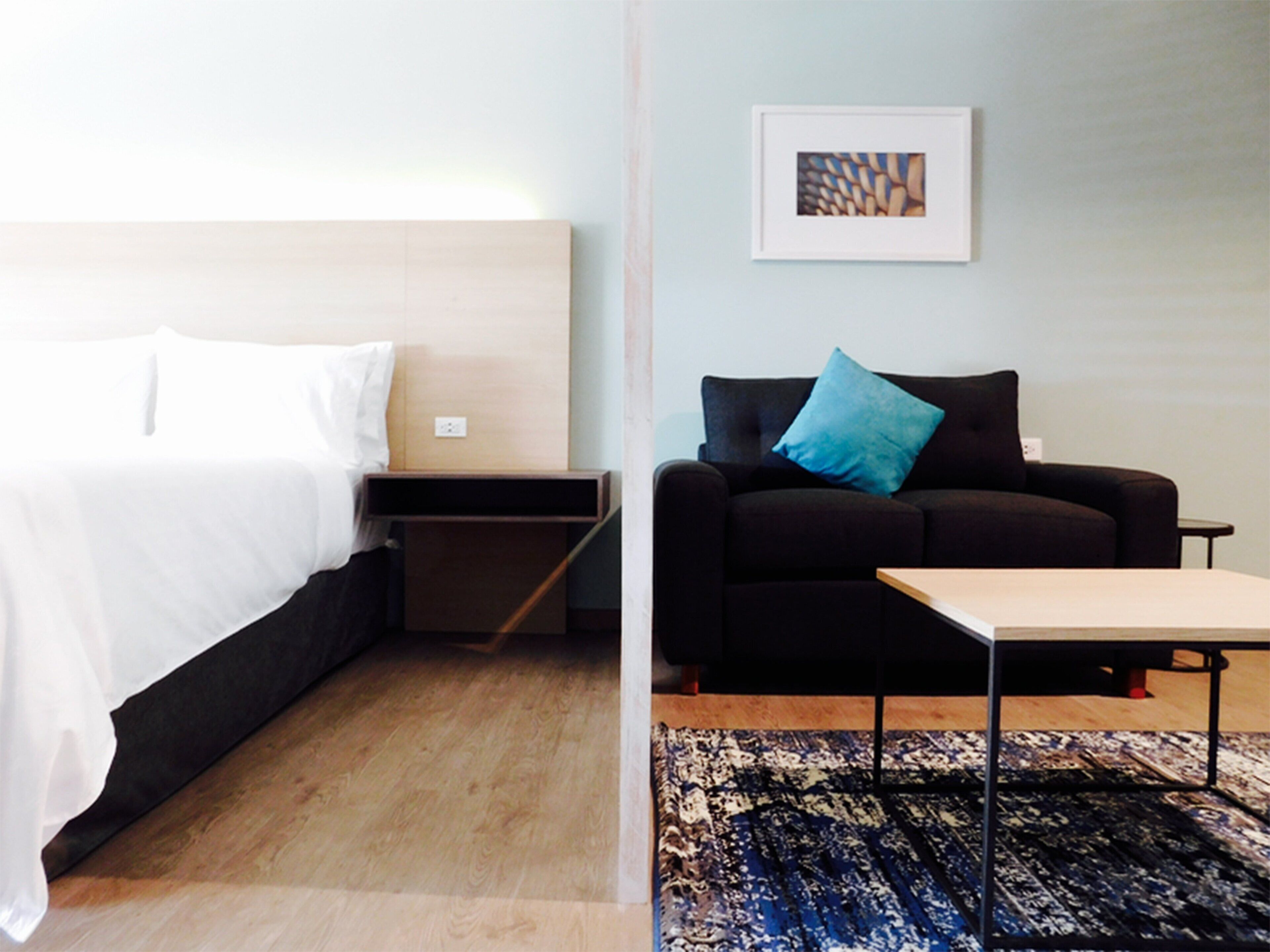 Ein Hotelzimmer mit Bett, einer Couch, einem kleinen Tisch und einem Teppich.