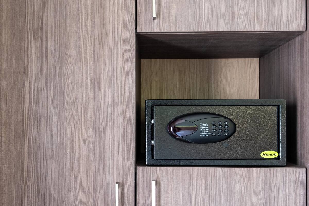 Een veilige kluis met een digitaal keypad, geplaatst in een houten kast met een handgreep.