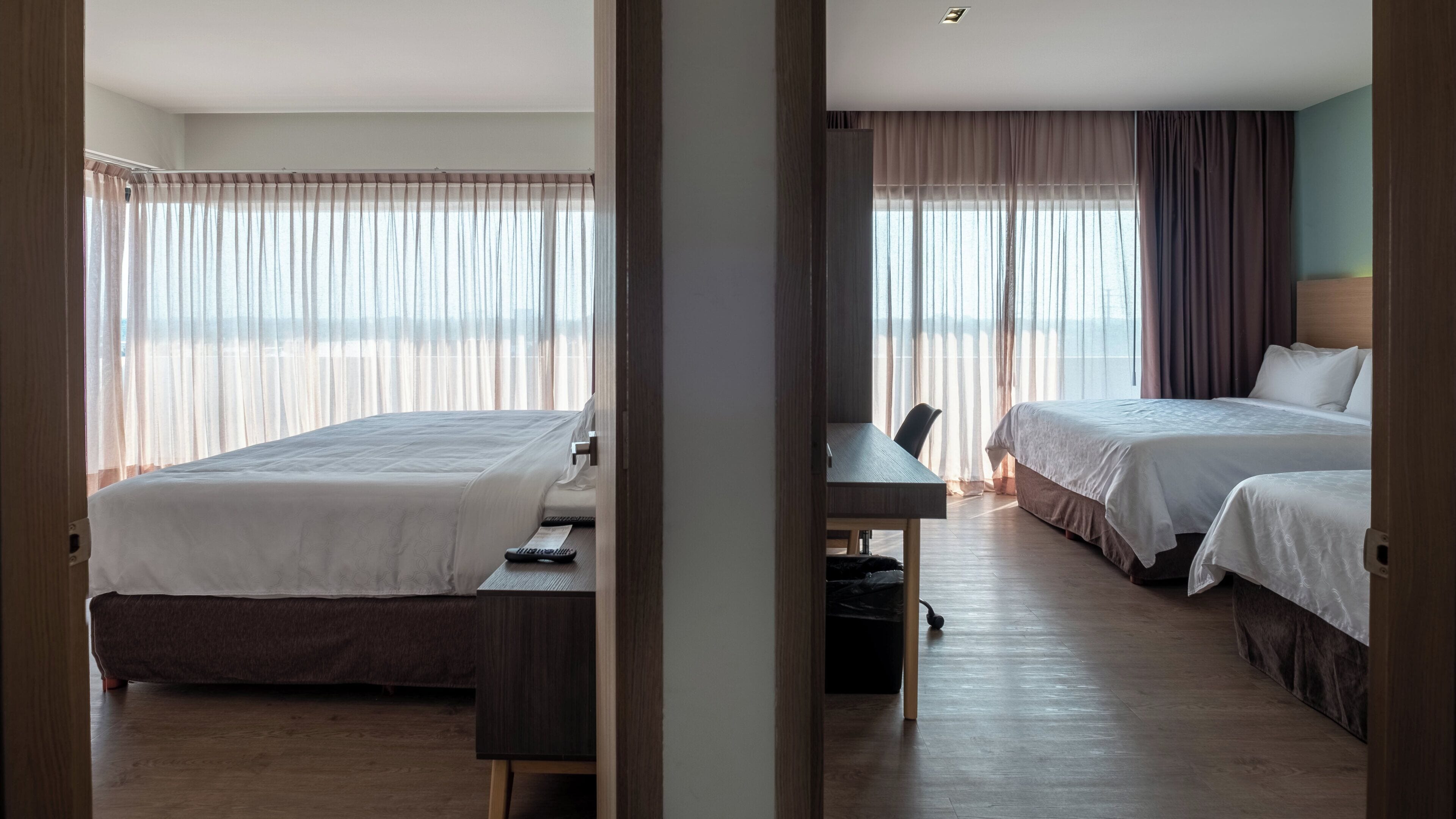 A hotel room with two beds, a desk, and a chair.
