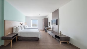 Ein modernes Hotelzimmer mit einem großen Bett, einem Schreibtisch, einem Fernseher und Blick ins Freie.