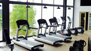 Un gimnasio con cuatro cintas de correr, una bicicleta estática y un banco para pesas.