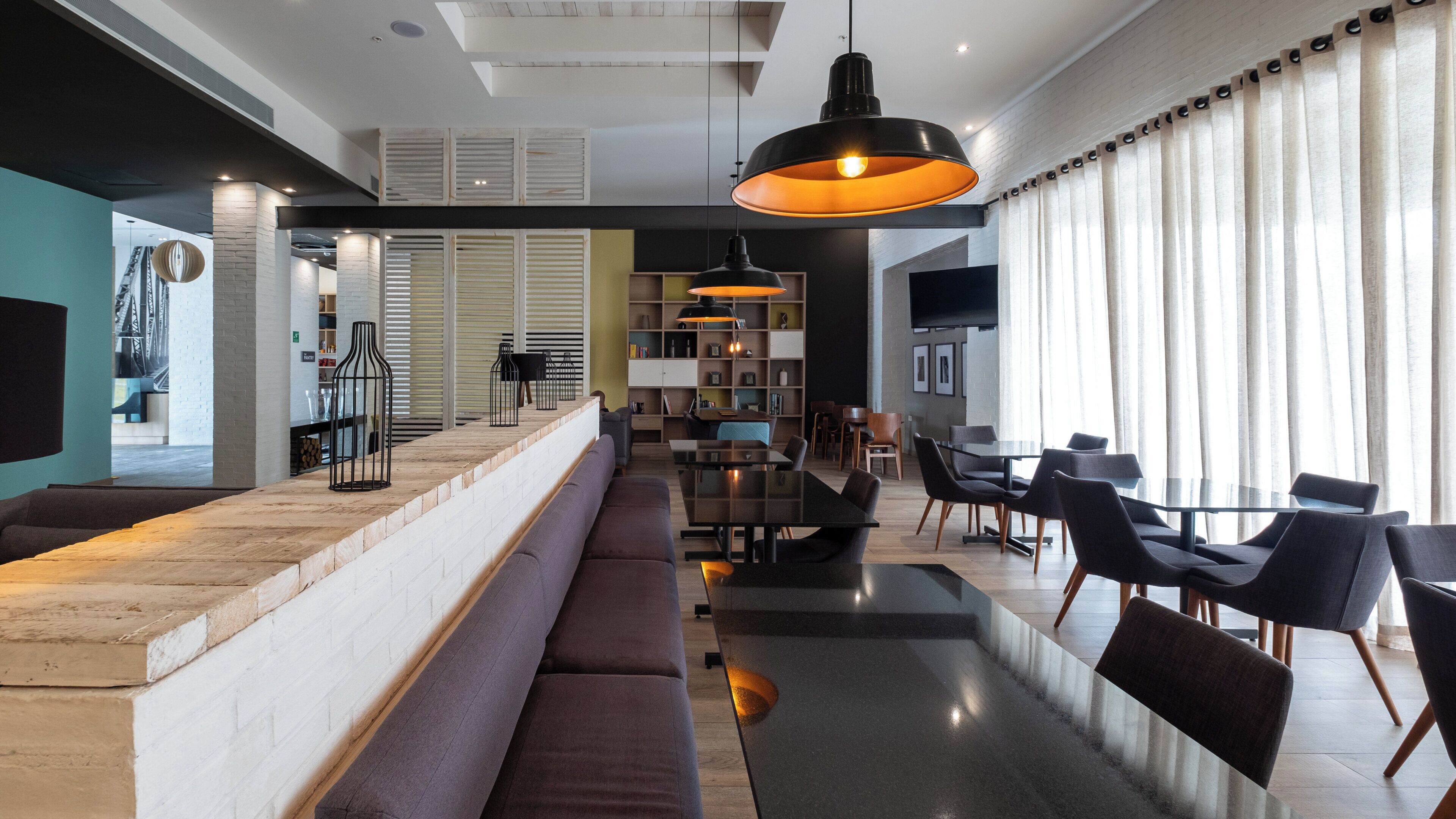 A modern interior with a long bar area, seating, and a dining space.