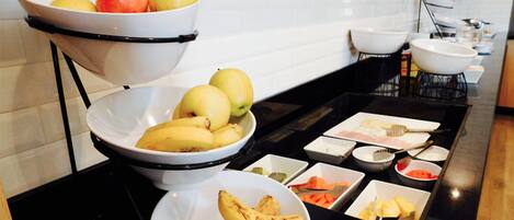 Un montaje tipo bufé con diversas frutas y platos.