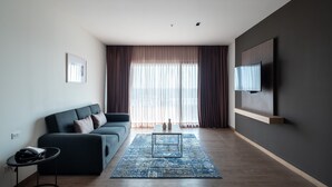Una sala de estar moderna con un sofá gris oscuro, un tapete estampado azul y un televisor montado en la pared.