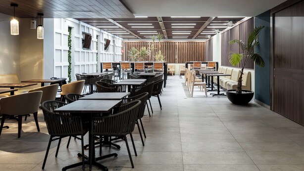 A modern conference room with tables and chairs, a wooden accent wall, and a potted plant. - Holiday Inn Express & Suites Playa Del Carmen by IHG (Playa del Carmen)