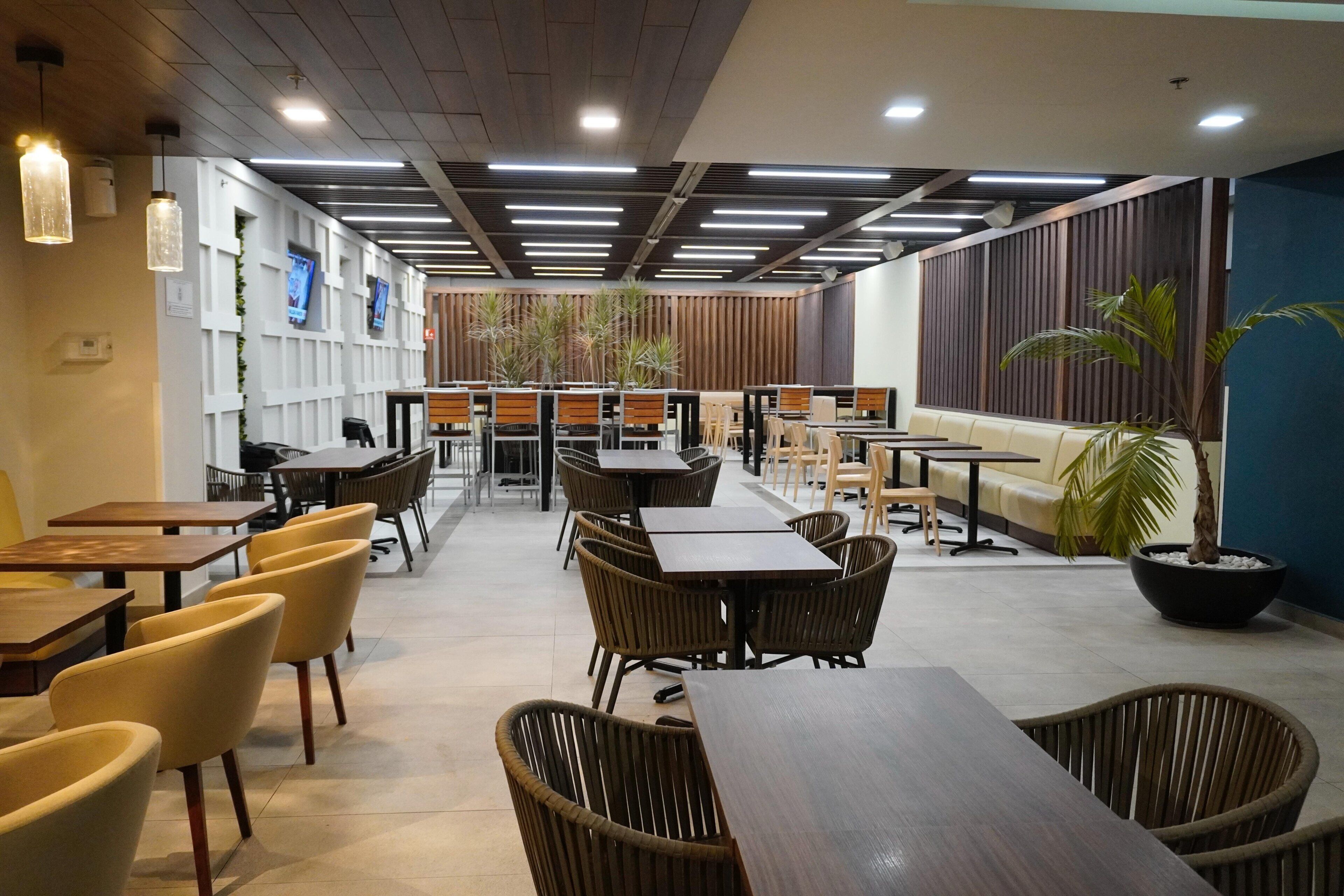 A modern indoor seating area with tables and chairs, a sofa, and a large potted plant.