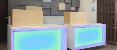 A reception desk with a modern design, featuring a check-in/check-out counter and a digital display.