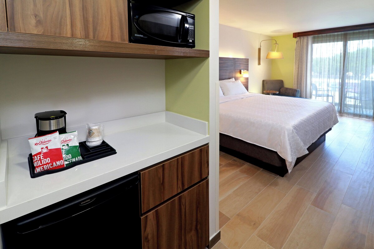 Une chambre d’hôtel équipée d’un lit, d’un bureau avec un micro-ondes et d’une machine à café.