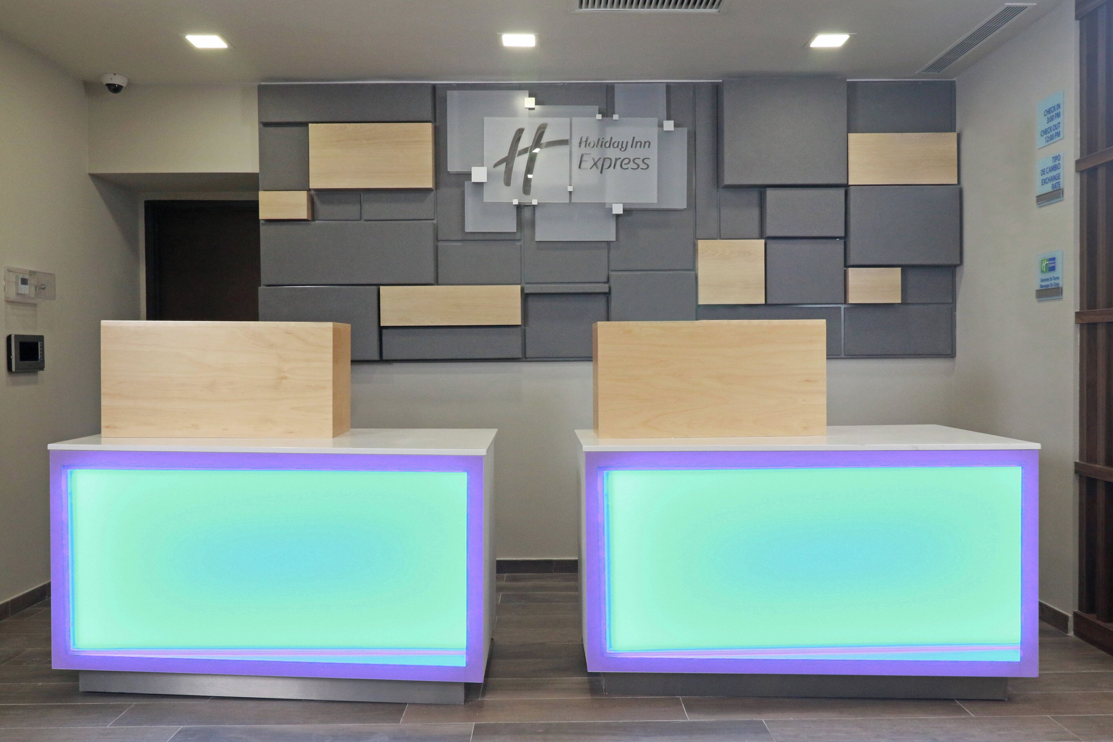 Vastaanottotiski, jossa on Holiday Inn Express -kyltti, sisäänkirjautumistiski ja seinälle kiinnitetty informaatiotaulu.