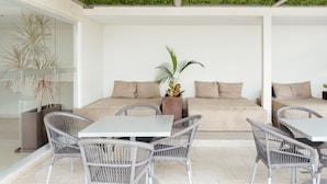 A modern outdoor seating area with wicker chairs, a white table, and a sofa with beige cushions. - Holiday Inn Express & Suites Playa Del Carmen by IHG (Playa del Carmen)