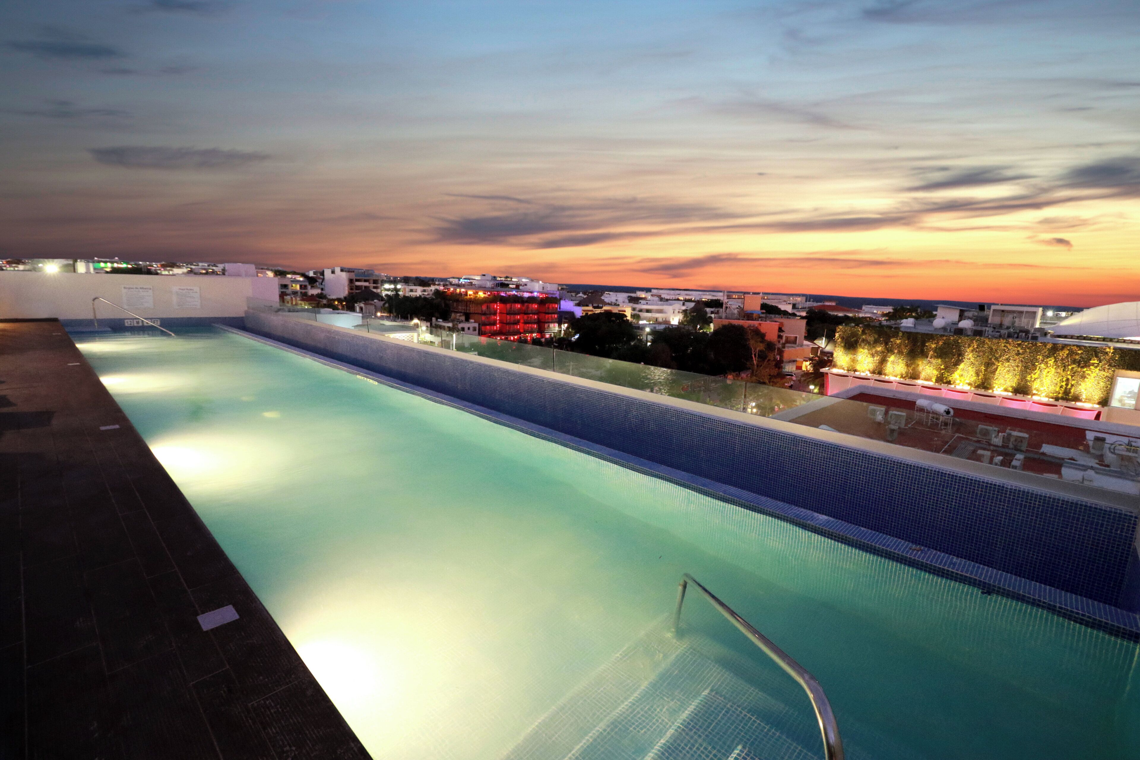 A swimming pool with a view of a cityscape at dusk.