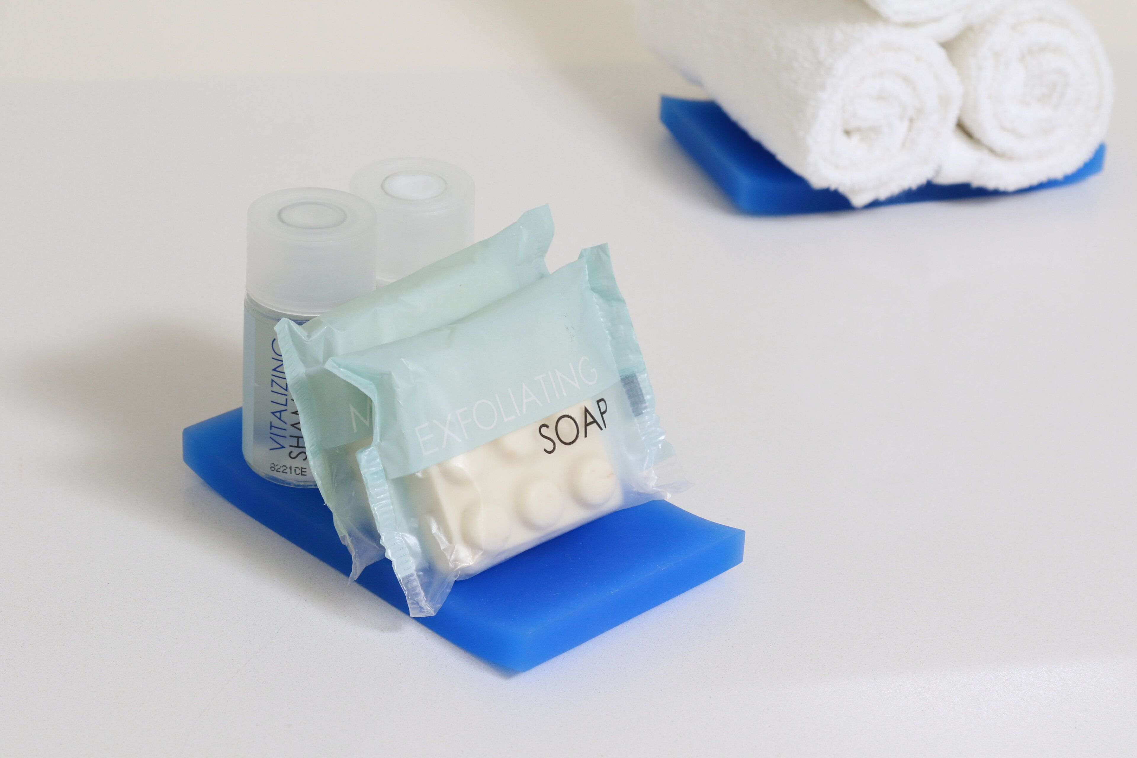 A blue soap dish with a bar of soap and a bottle of hand sanitizer.