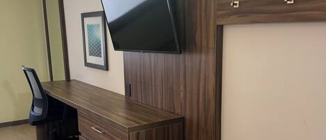 Un espacio de oficina moderno con un escritorio de madera, una silla de oficina negra y un televisor de pantalla plana montado en la pared.