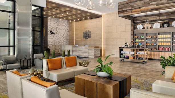A modern lobby with a seating area, a coffee station, and a brick wall. - Holiday Inn & Suites Nashville Downtown - Broadway by IHG (Nashville)