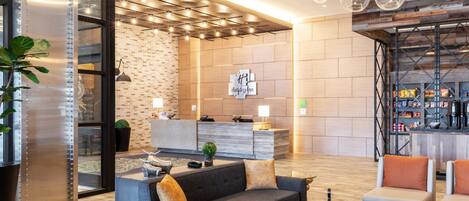 A modern lobby with a reception desk, seating area, and a bar.