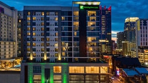 A multi-story hotel with a Holiday Inn sign, large windows, and a prominent vertical structure. - Holiday Inn & Suites Nashville Downtown - Broadway by IHG (Nashville)