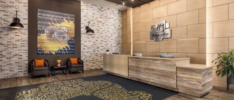 A reception area with a brick wall, a wooden reception desk, and a large poster on the wall.