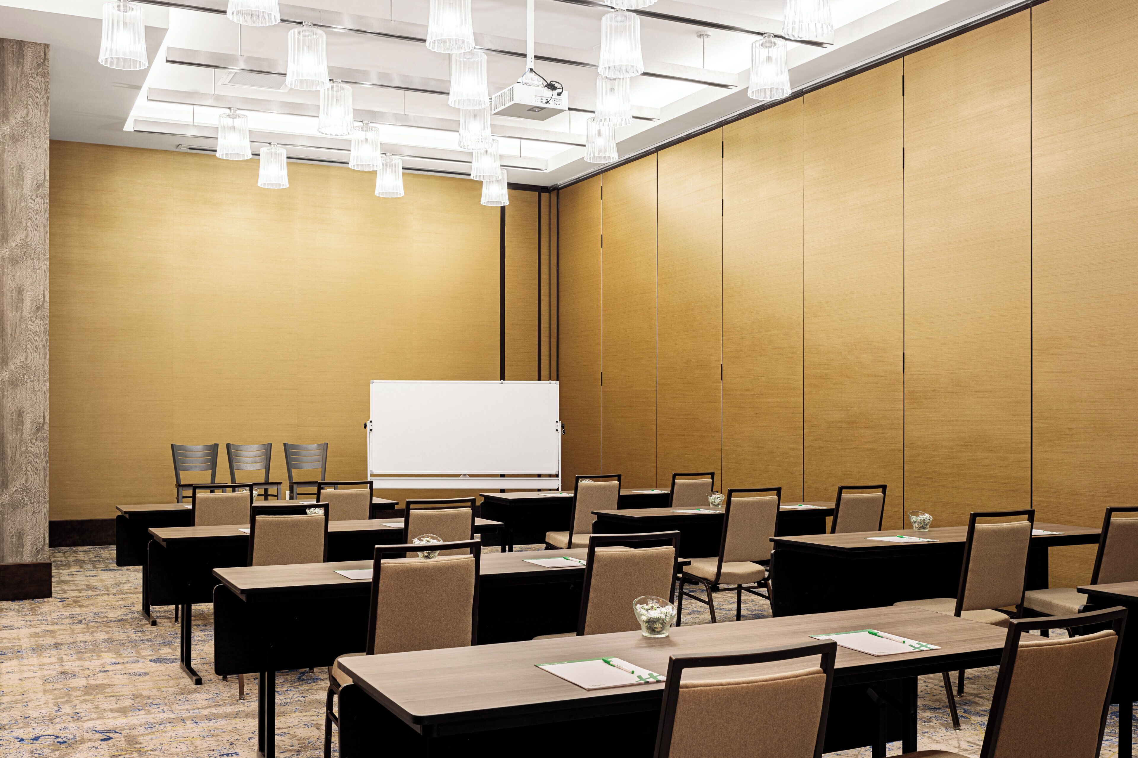 Una sala de conferencias con mesas, sillas, una pizarra y un proyector.