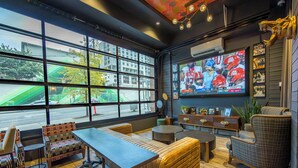 A modern interior with large windows, a TV displaying a sports game, and a seating area with a table and chairs. - Holiday Inn & Suites Nashville Downtown - Broadway by IHG (Nashville)
