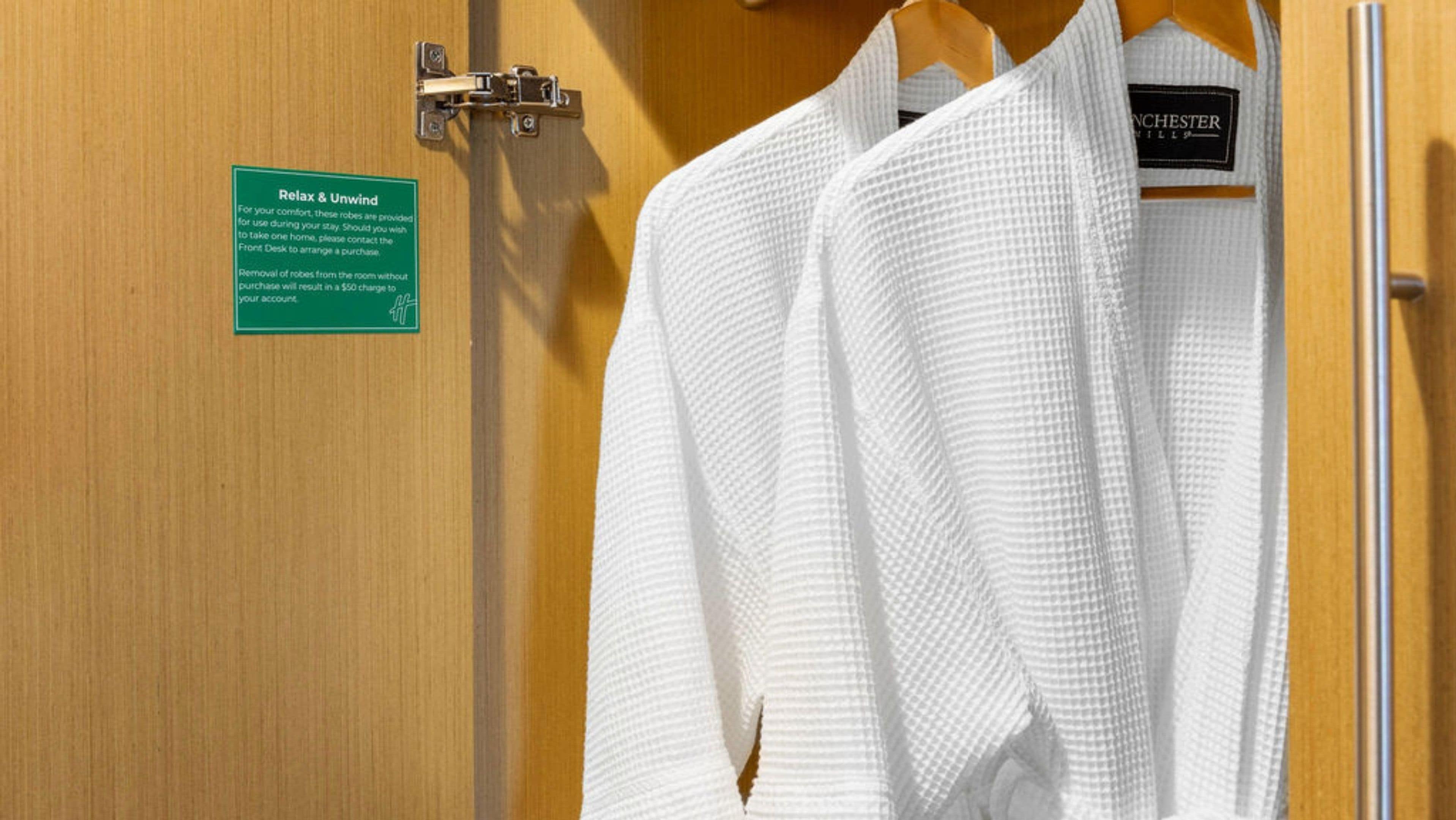 Una puerta de madera con un letrero que indica un espacio de relajación y una bata blanca colgada de un perchero.
