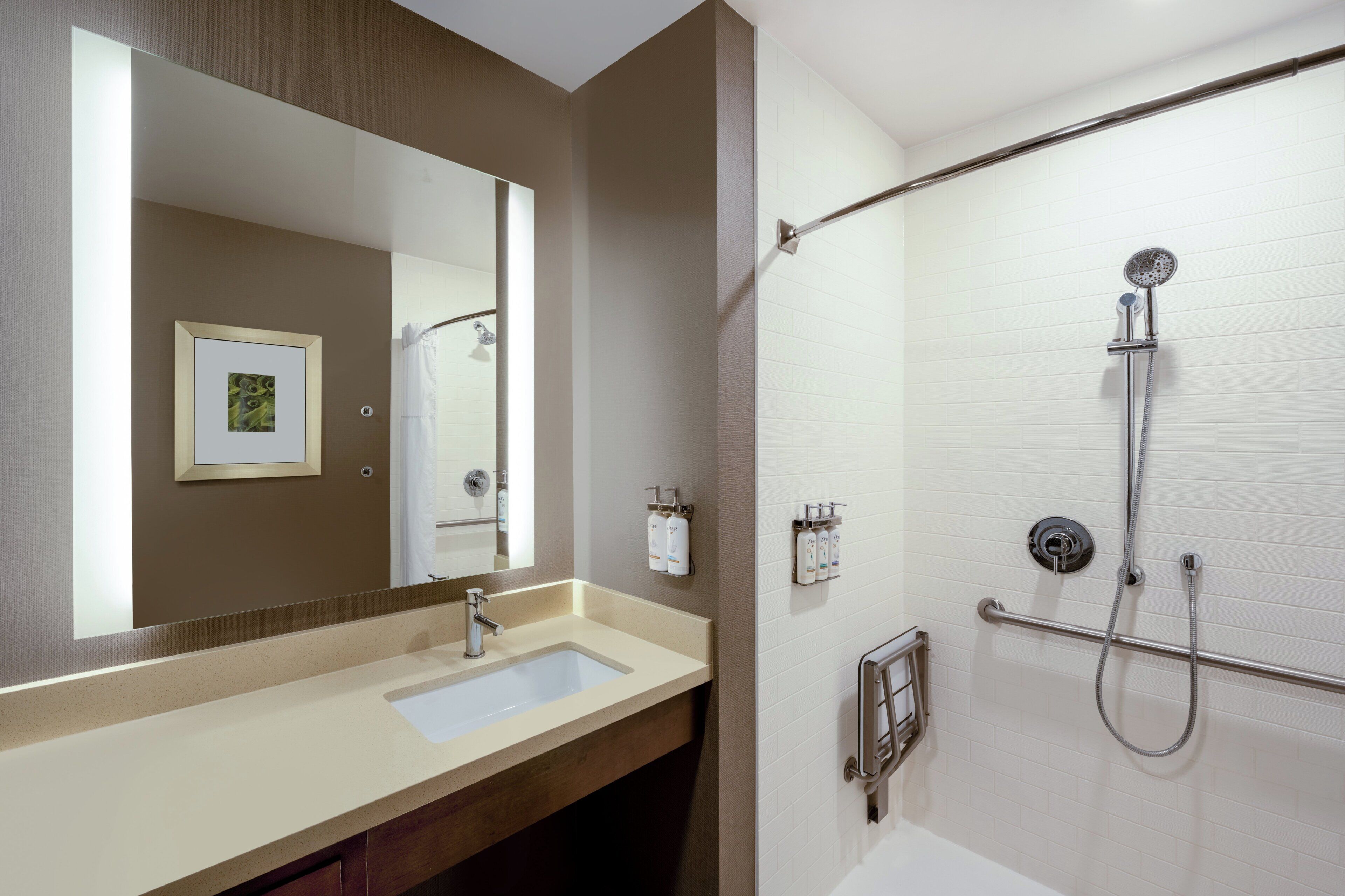 A bathroom with a sink, mirror, shower, and toiletries.