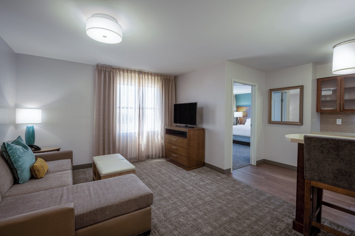 A hotel room with a sofa, a television, a desk, and a mirror.