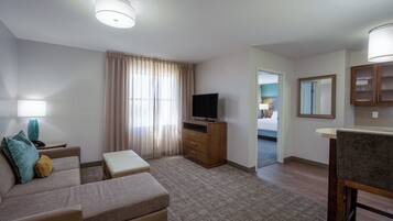 Habitación de hotel con sofá, televisión, escritorio y espejo.