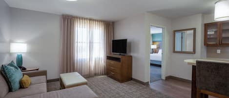 Ett hotellrum med en soffa, en tv, ett skrivbord och en spegel.