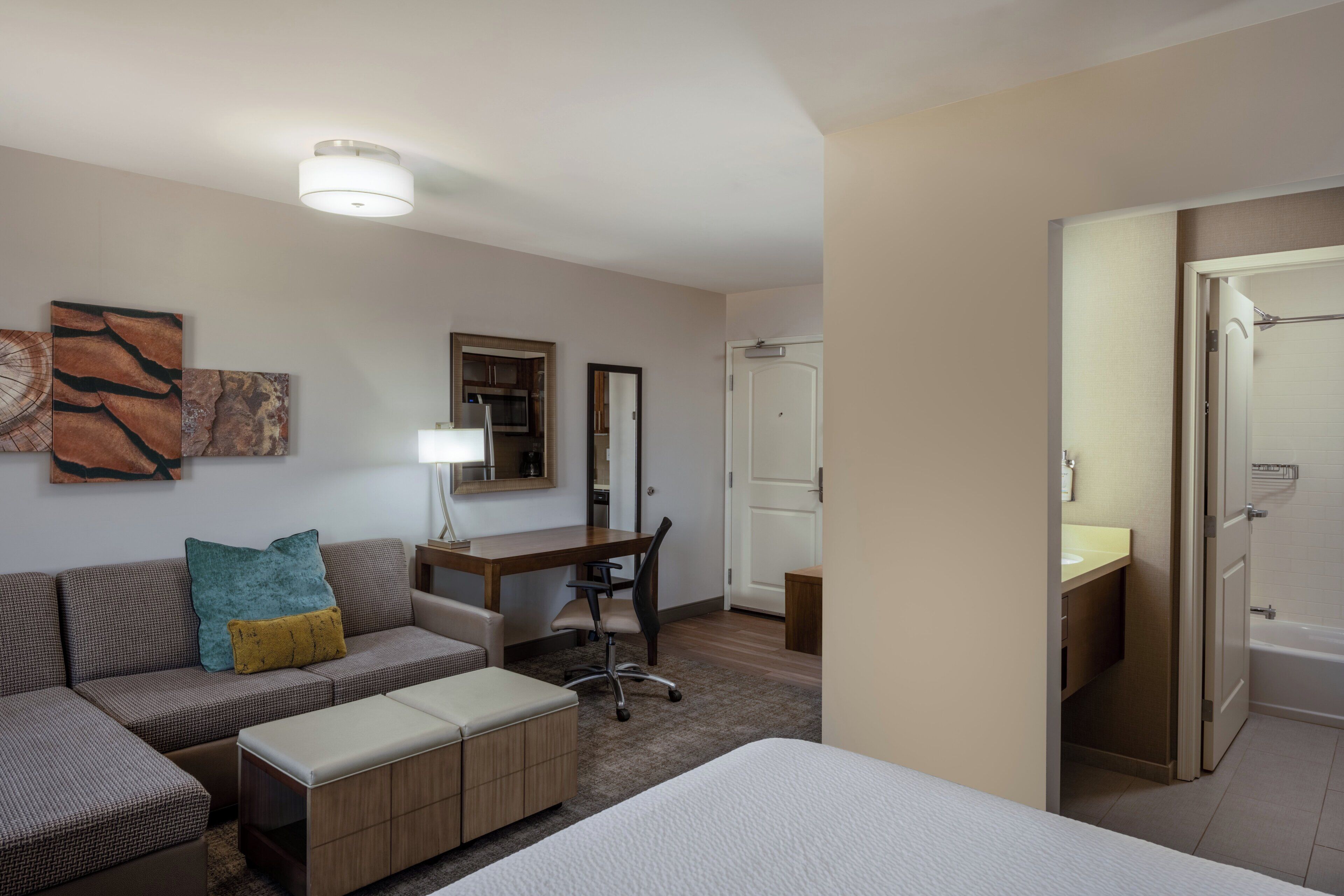 A hotel room with a bed, a sofa, a desk, a chair, and a bathroom.