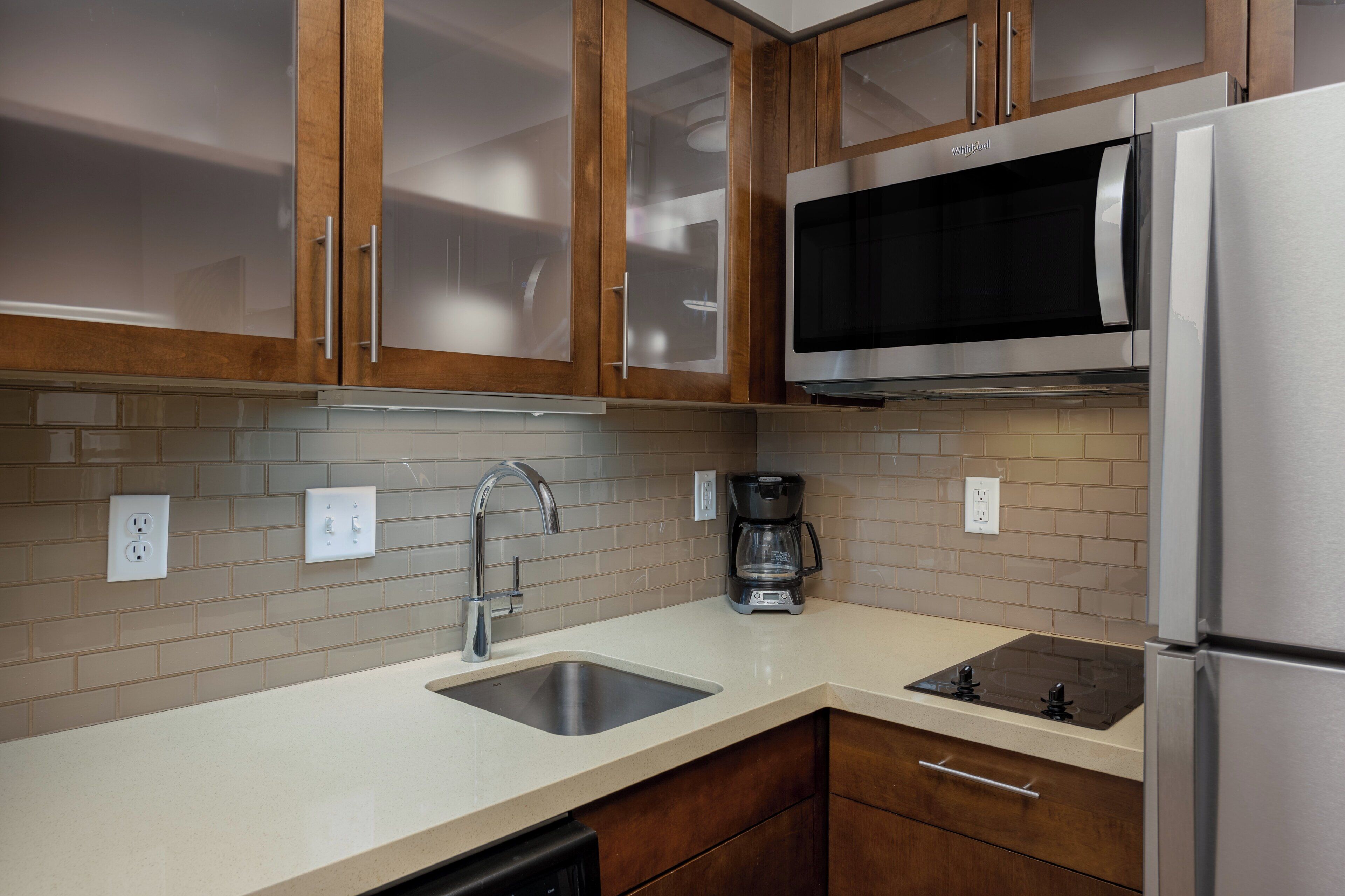 A kitchen with wooden cabinets, a stainless steel refrigerator, a microwave, a coffee maker, and a dishwasher.