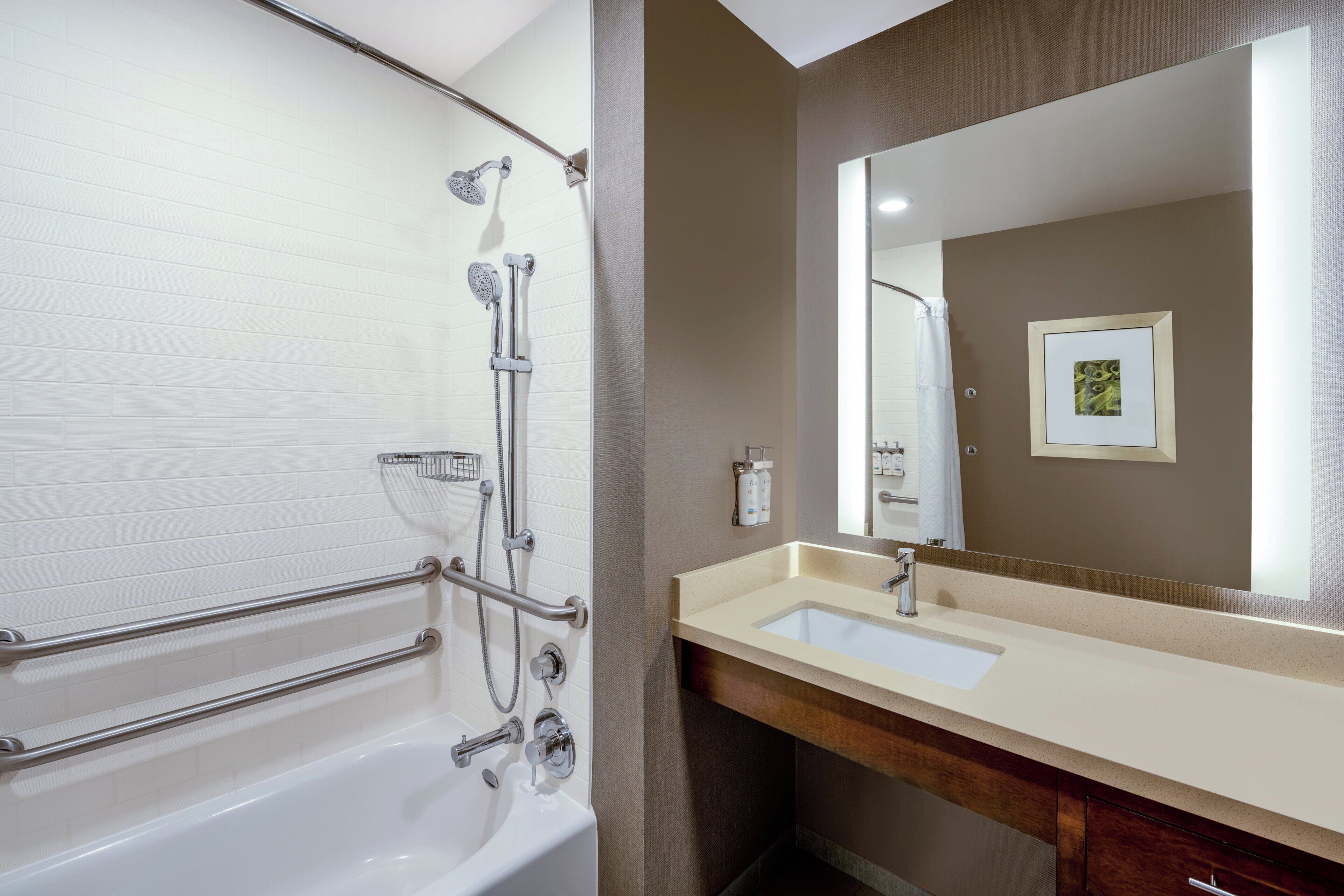 A bathroom with a bathtub, shower, vanity, and a large mirror.