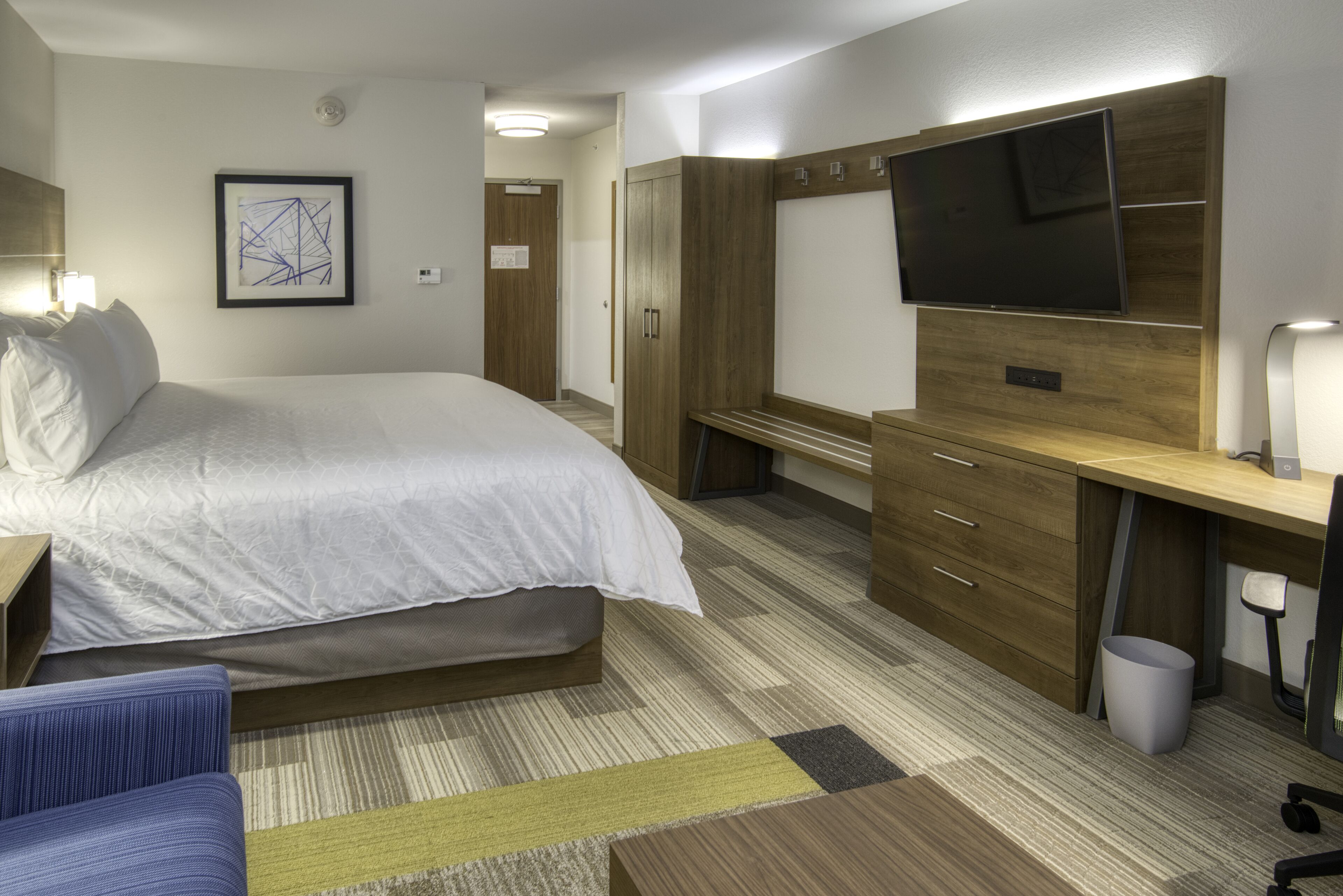 Une chambre d’hôtel équipée d’un lit, d’un bureau, d’une télévision et d’une armoire.