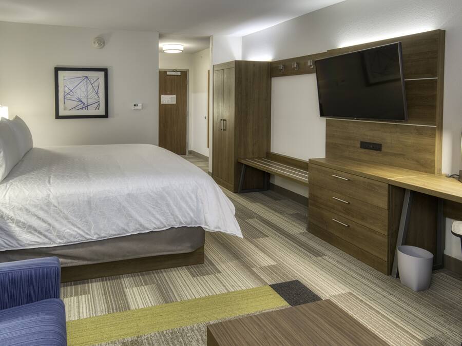 A hotel room with a bed, a desk, a television, and a wardrobe.