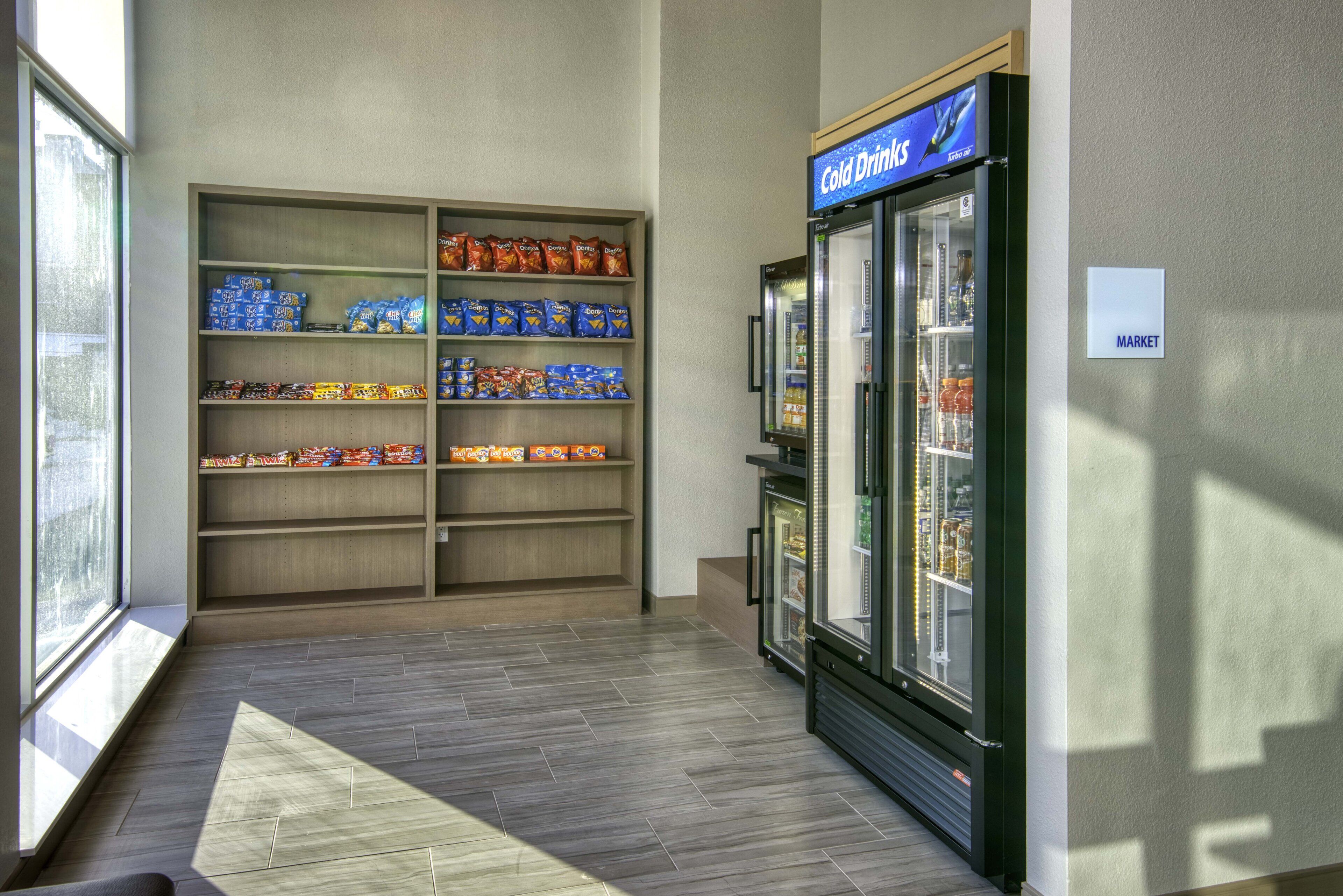 A snack area with shelves stocked with various snacks and a refrigerated display case labeled "Cold Drinks".