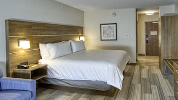 Une chambre d’hôtel avec un grand lit, des tables de chevet, une chaise et une tête de lit en bois.