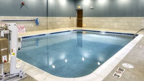 Une piscine avec un poste de surveillance pour le sauveteur, un panneau de signalisation et une porte en arrière-plan.