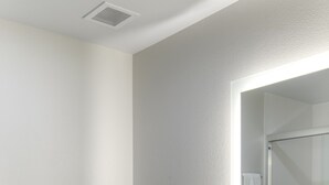 A modern bathroom with a white sink, a mirror, and a toilet.