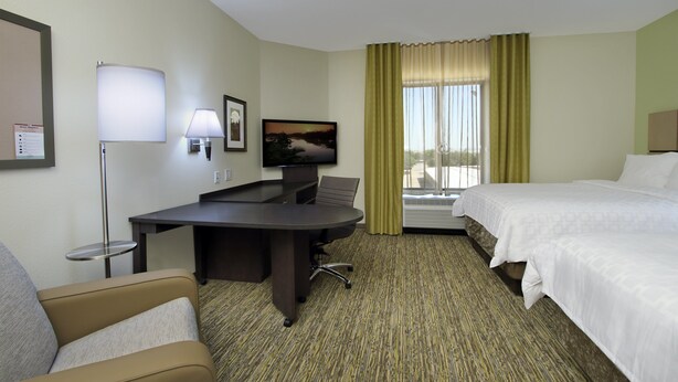 A hotel room with a bed, a desk with a chair, a television, and a window with curtains. - Candlewood Suites Dallas-Frisco NW Toyota Ctr by IHG (Frisco)