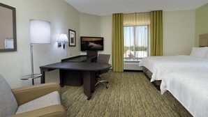 Habitación de hotel con cama, escritorio con silla, televisión y ventana con cortinas.