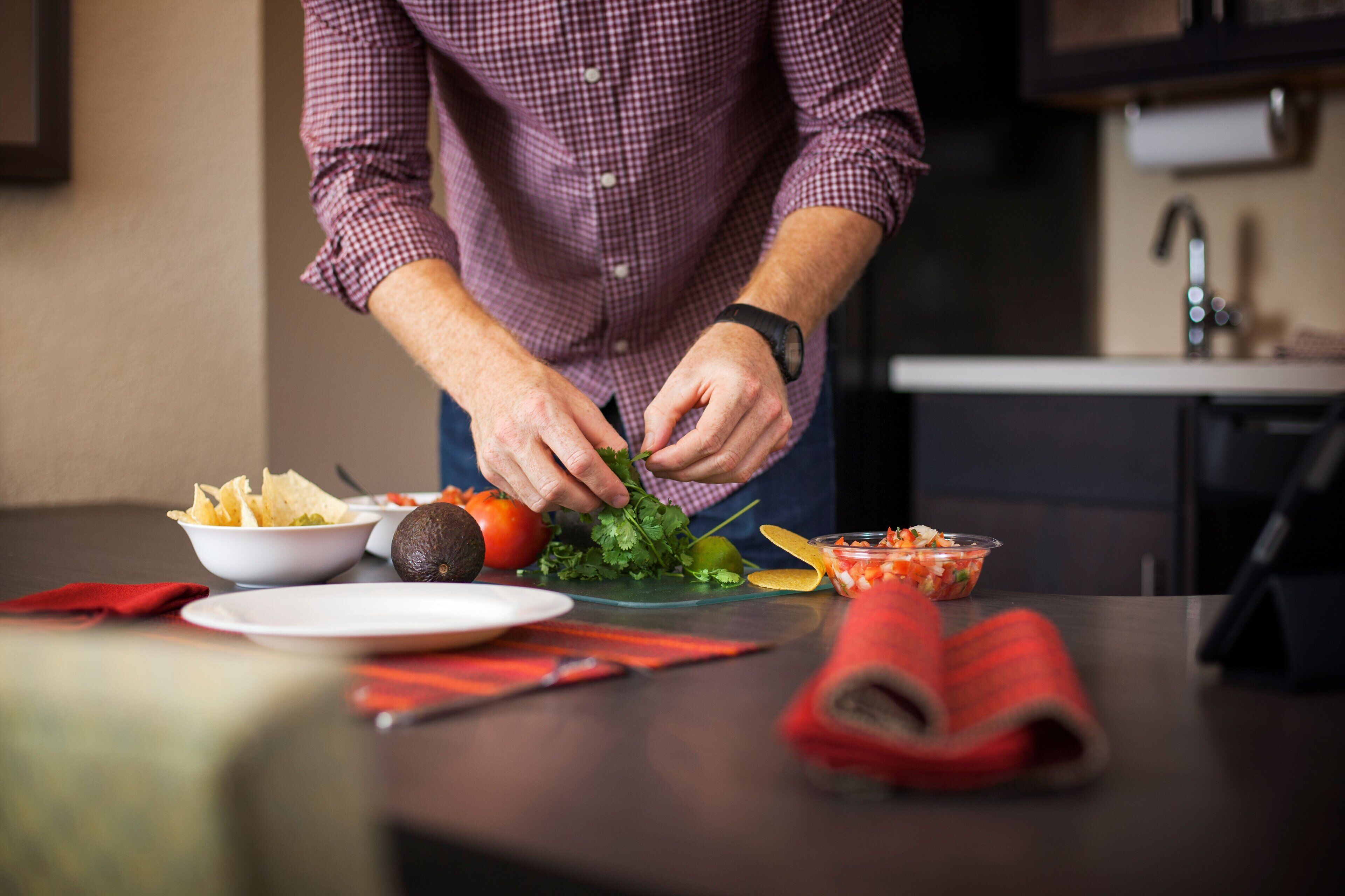 Una persona preparando comida con diversos ingredientes y platos sobre una mesa.