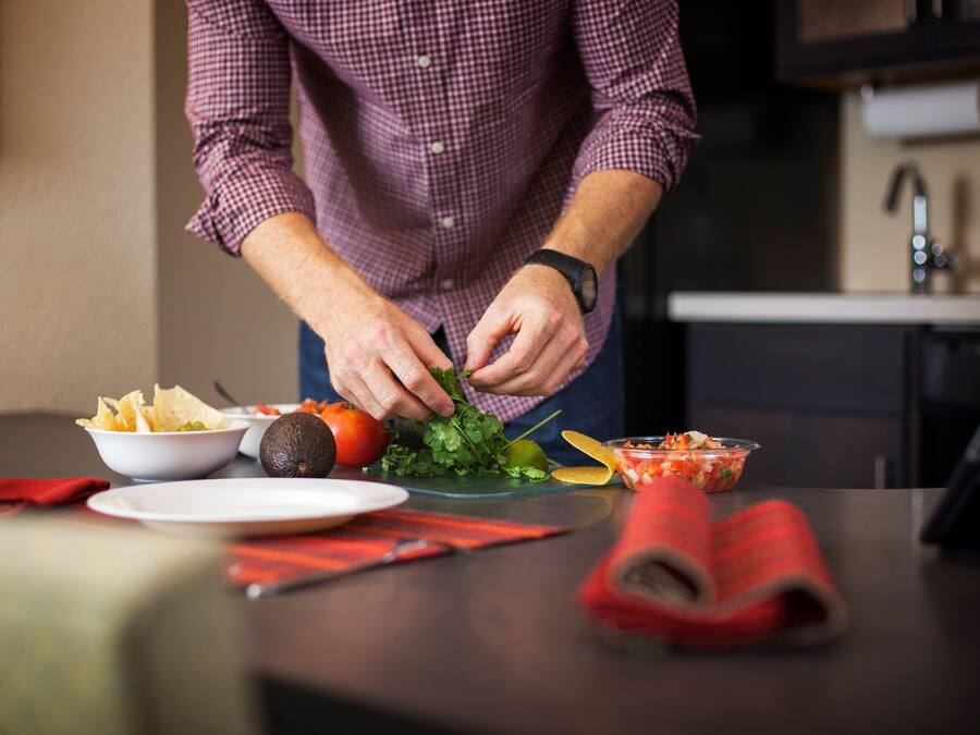 A person preparing food with various ingredients and dishes on a table.