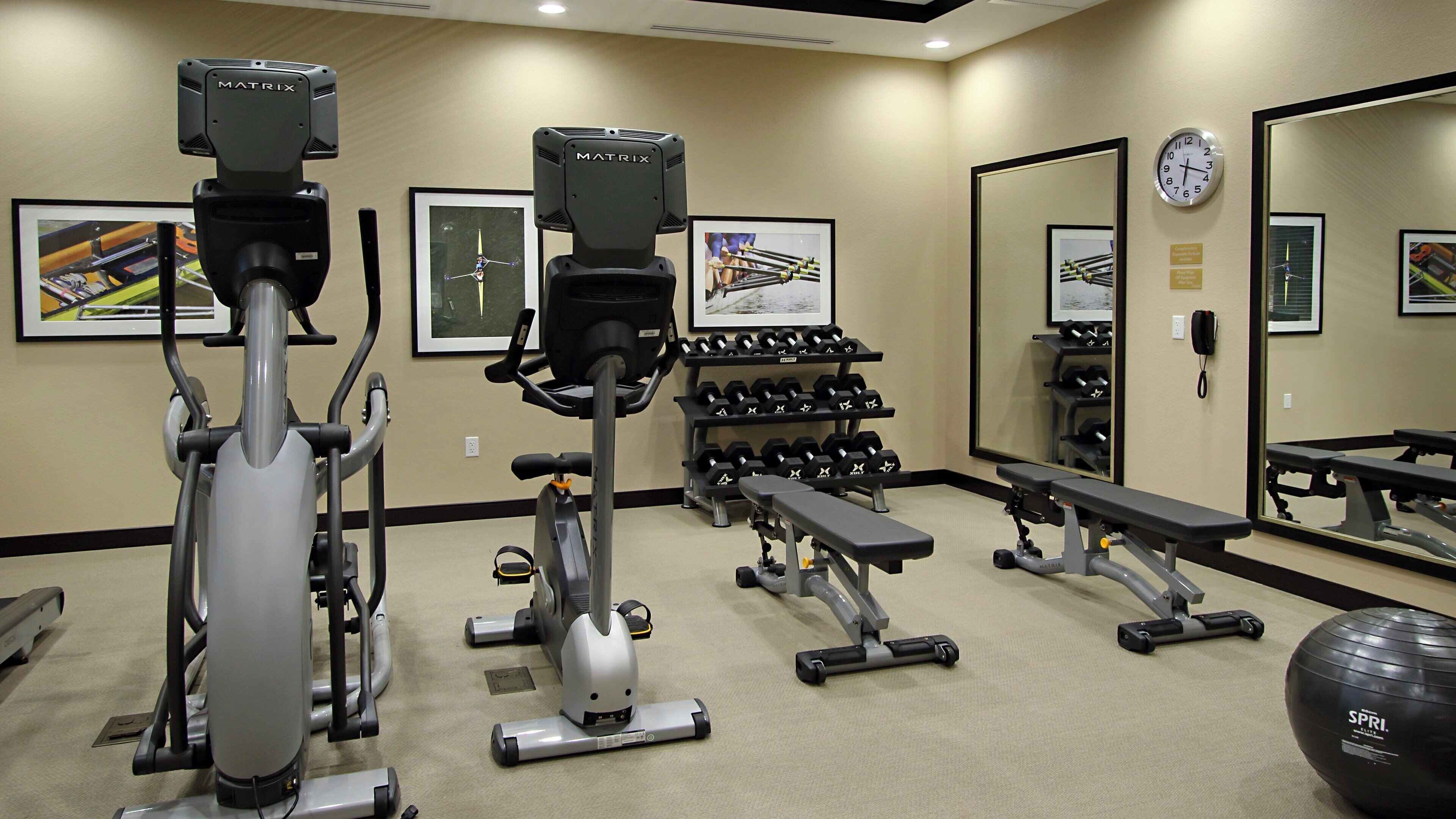 Una palestra con diverse attrezzature per esercizi, tra cui tapis roulant, cyclette e manubri.