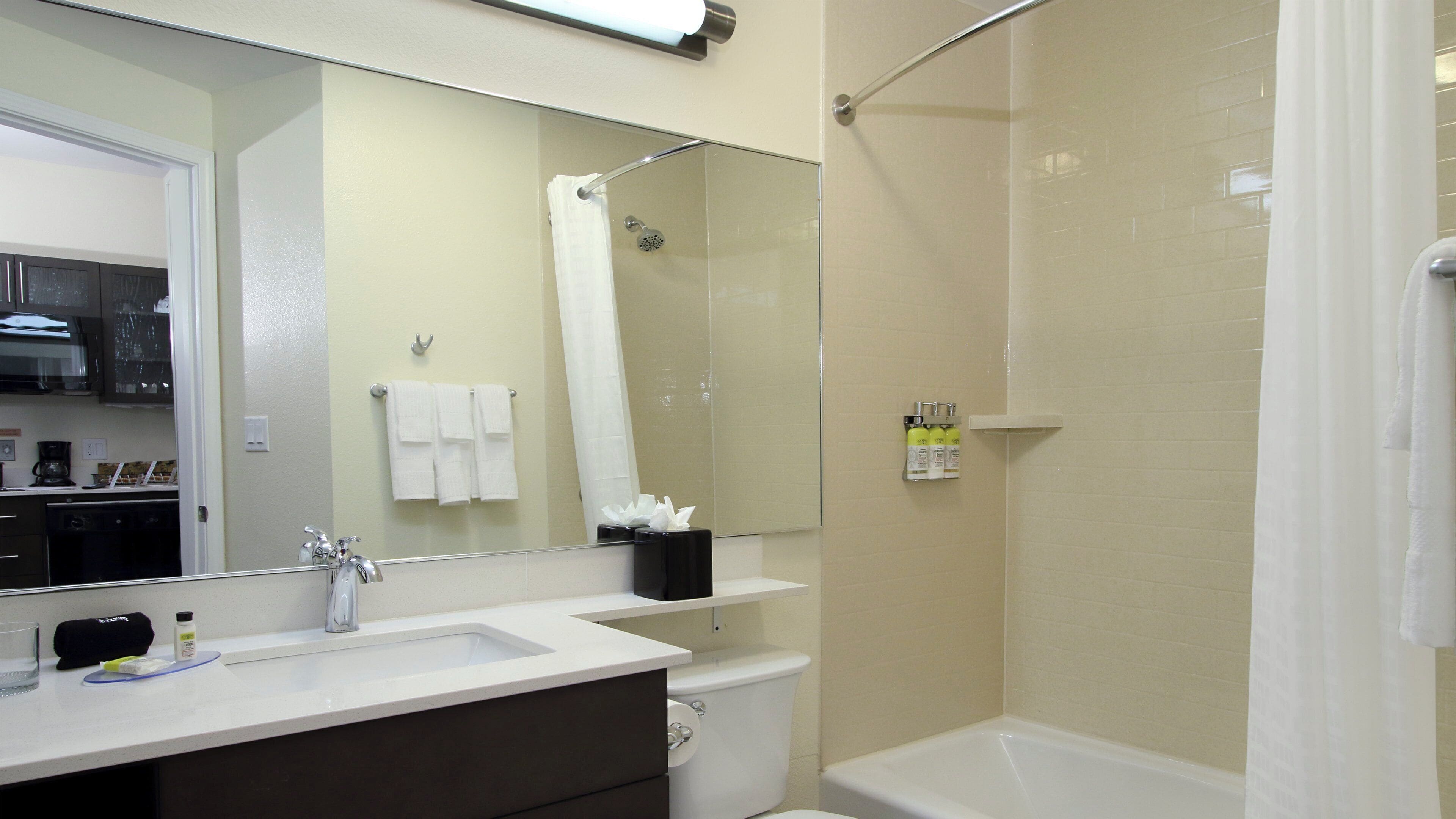 Un baño con lavamanos, espejo, inodoro y ducha.