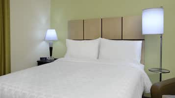 Una habitación de hotel con cama, mesita de noche, lámpara y mesilla.
