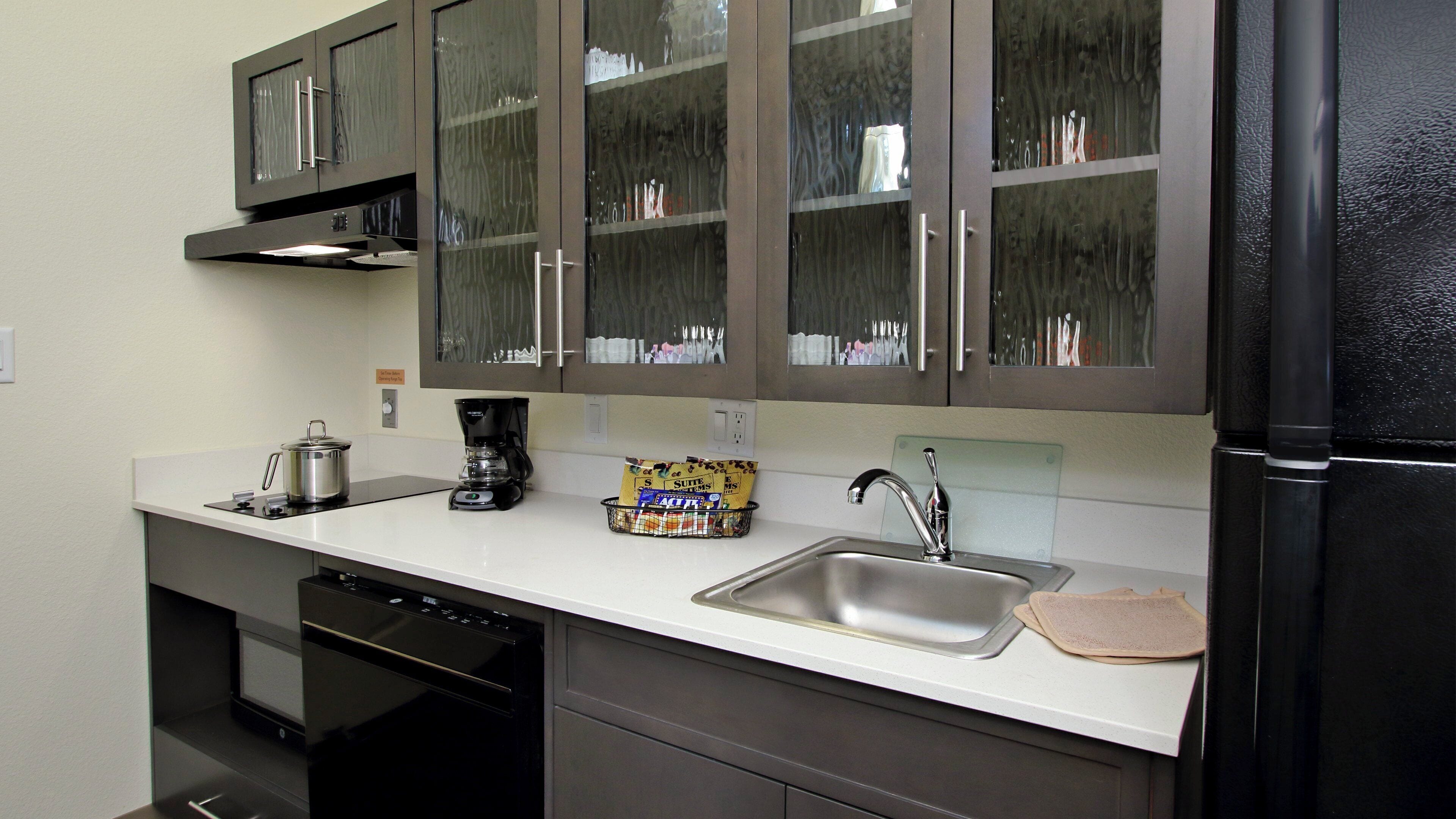 A modern kitchen with stainless steel appliances, a coffee maker, and a basket of snacks.