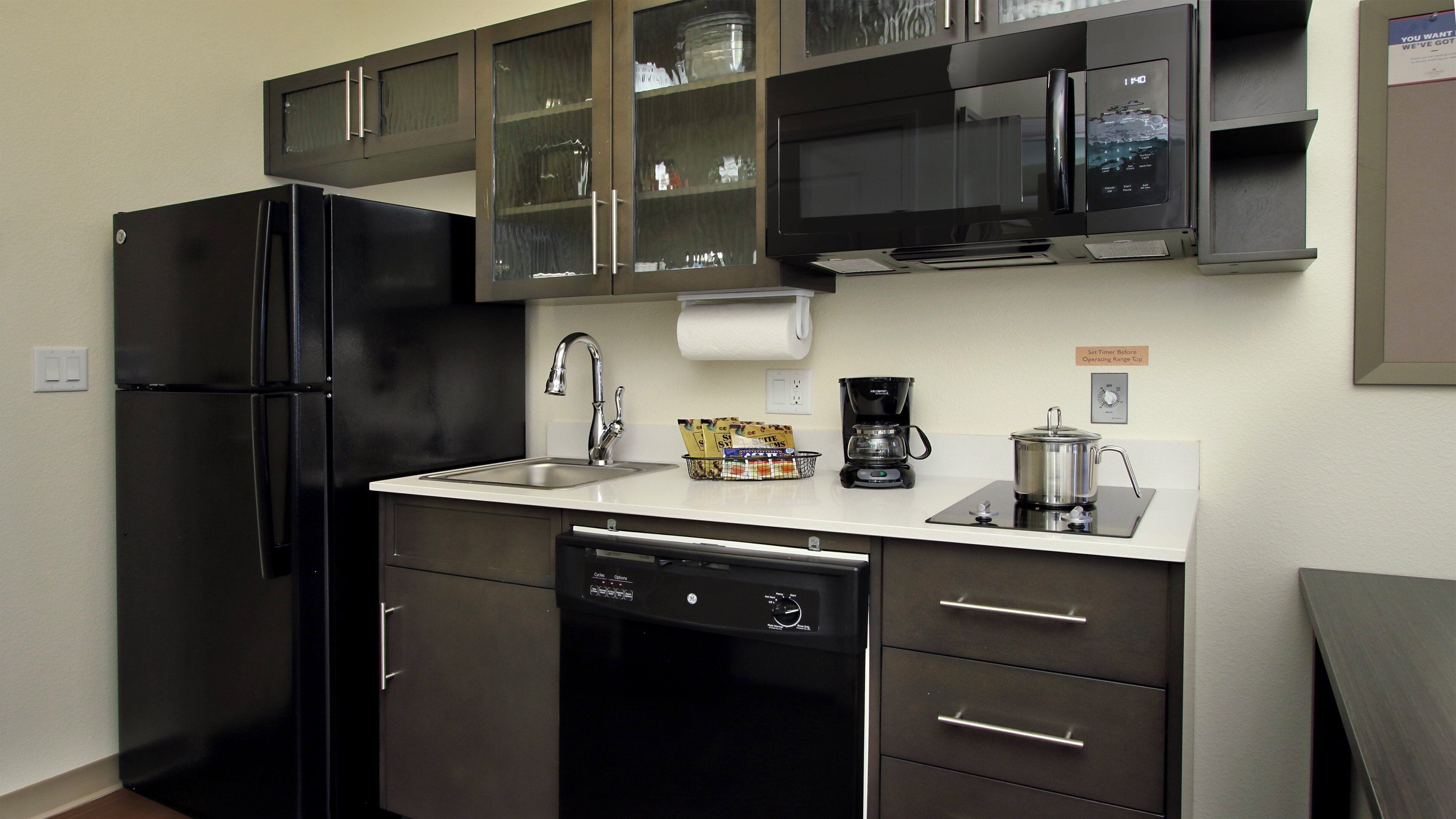 Una cocina moderna equipada con refrigerador, lavavajillas, microondas, cafetera y un cartel de temporizador.