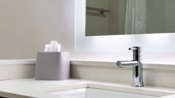 Un lavabo amb aixeta cromada, suport de mocadors i un mirall a la part superior.