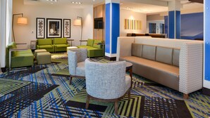A lobby with a patterned carpet, green and grey seating, and a large sofa. - Holiday Inn Express & Suites Ottumwa by IHG (Ottumwa)