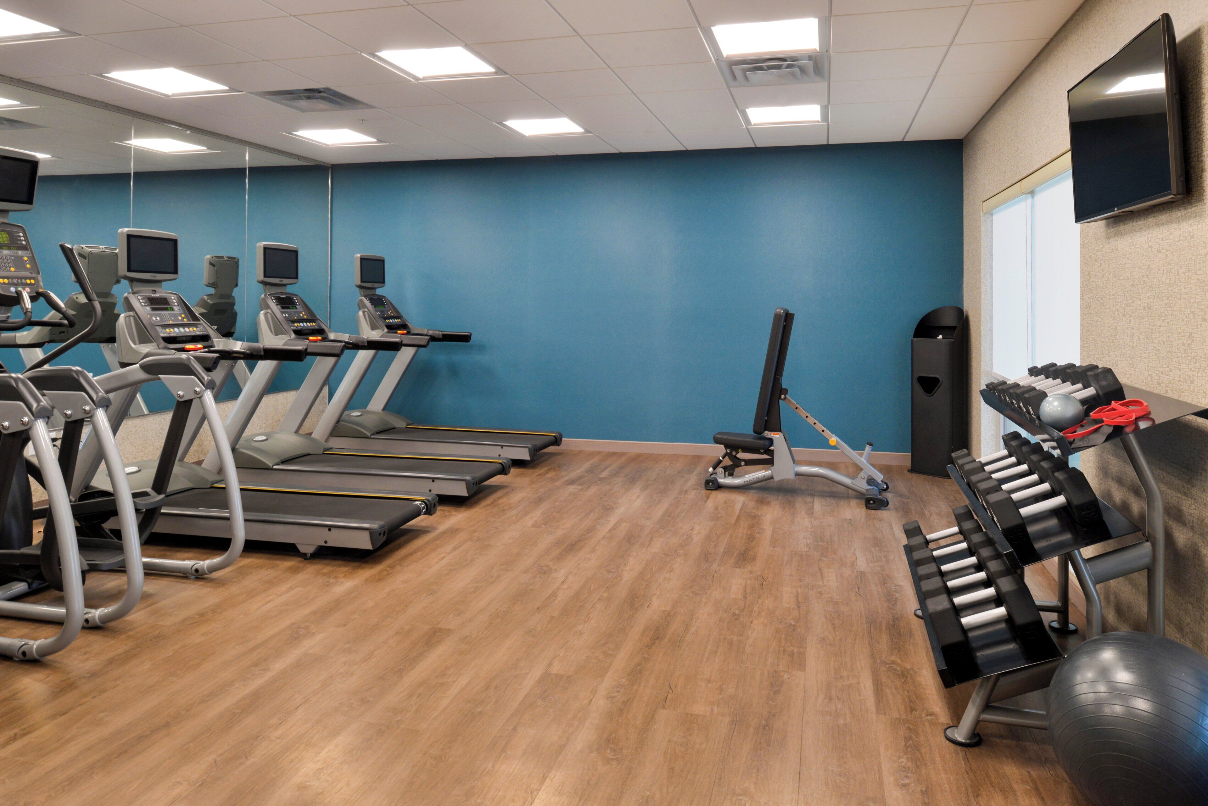 Een sportschool met loopbanden, krachtapparaten en fitnessballen.